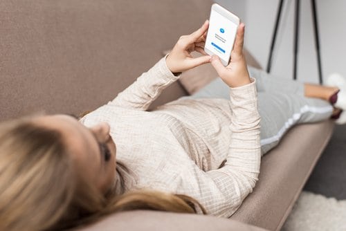 woman lying down looking at the phone