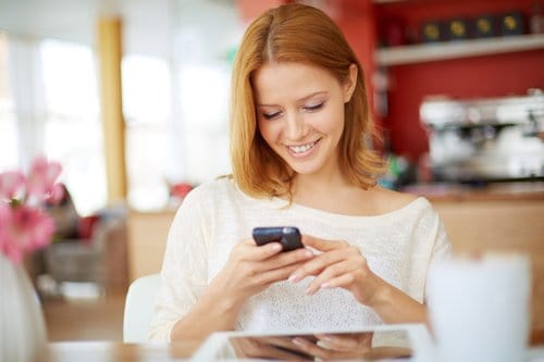 Image of young female reading sms on the phone in cafe